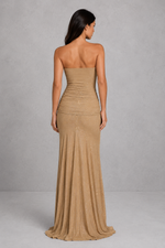 Woman wearing a beige strapless gown against a gray background