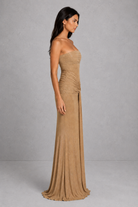 Woman wearing a beige strapless gown against a gray background