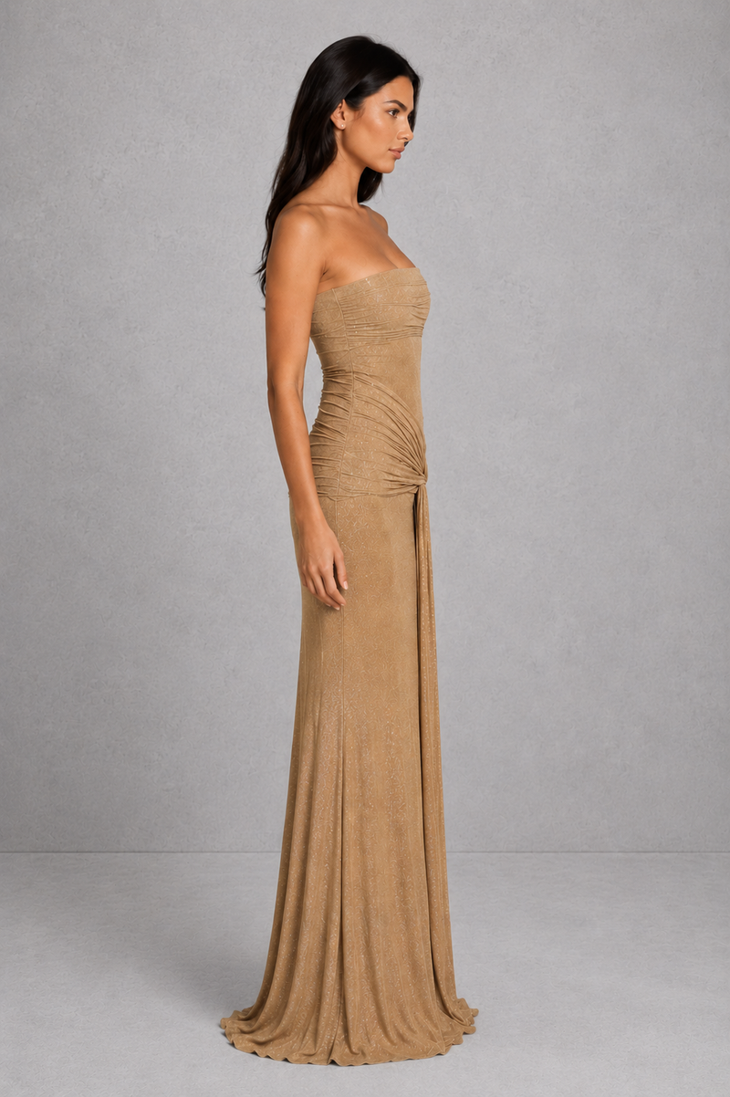 Woman wearing a beige strapless gown against a gray background