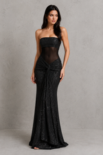 Woman wearing a black strapless gown with sheer overlay against a gray background