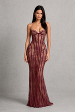 Woman wearing a burgundy strapless gown against a gray background