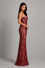 Woman wearing a burgundy strapless gown against a gray background