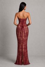 Woman wearing a burgundy lace evening gown against a gray background