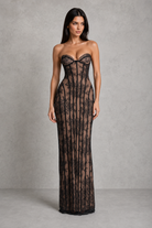 Woman wearing a black lace strapless gown against a gray background