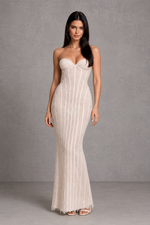 Woman wearing a strapless white evening gown against a gray background