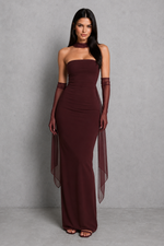 Woman wearing a burgundy strapless gown with sheer sleeves against a gray background