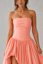 Woman wearing a strapless coral dress against a gray background