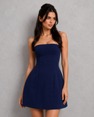 Woman wearing a navy strapless dress against a gray background
