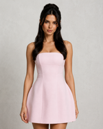 Woman wearing a pink strapless dress against a plain background