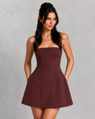 Woman wearing a burgundy strapless dress against a gray background