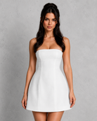 Woman wearing a white strapless dress against a gray background