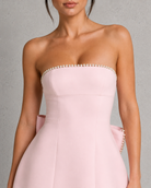 Pink strapless dress with pearl detailing on a neutral background