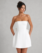 Woman wearing a white strapless dress against a gray background