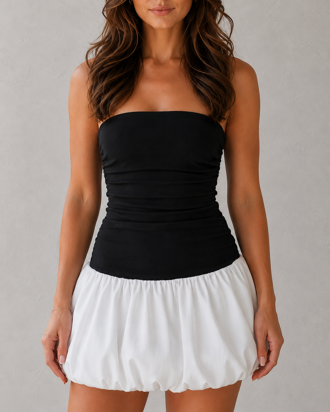 Woman wearing a black strapless top and white skirt against a gray background
