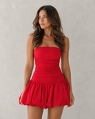 Woman wearing a red strapless dress against a plain background