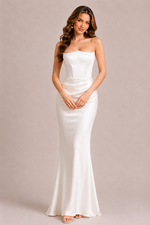 Woman wearing a white strapless gown against a plain background