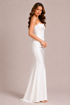 Woman wearing a white strapless gown against a beige background