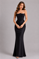 Woman wearing a black strapless gown against a gray background