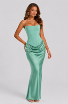 Woman wearing a strapless green gown on a gray background
