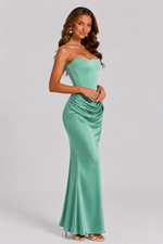 Woman wearing a strapless green evening gown on a gray background