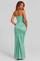 Woman wearing a strapless green evening gown on a light gray background