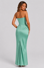 Woman wearing a strapless green evening gown on a light gray background
