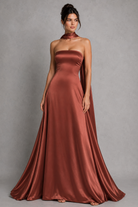 Woman wearing a strapless rust-colored gown against a gray background