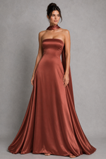 Woman wearing a strapless rust-colored gown against a gray background