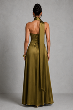 Woman wearing a long green dress with a halter neck design against a gray background