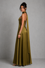 Woman wearing an olive green evening gown against a gray background