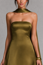 Woman wearing a strapless gold dress against a gray background