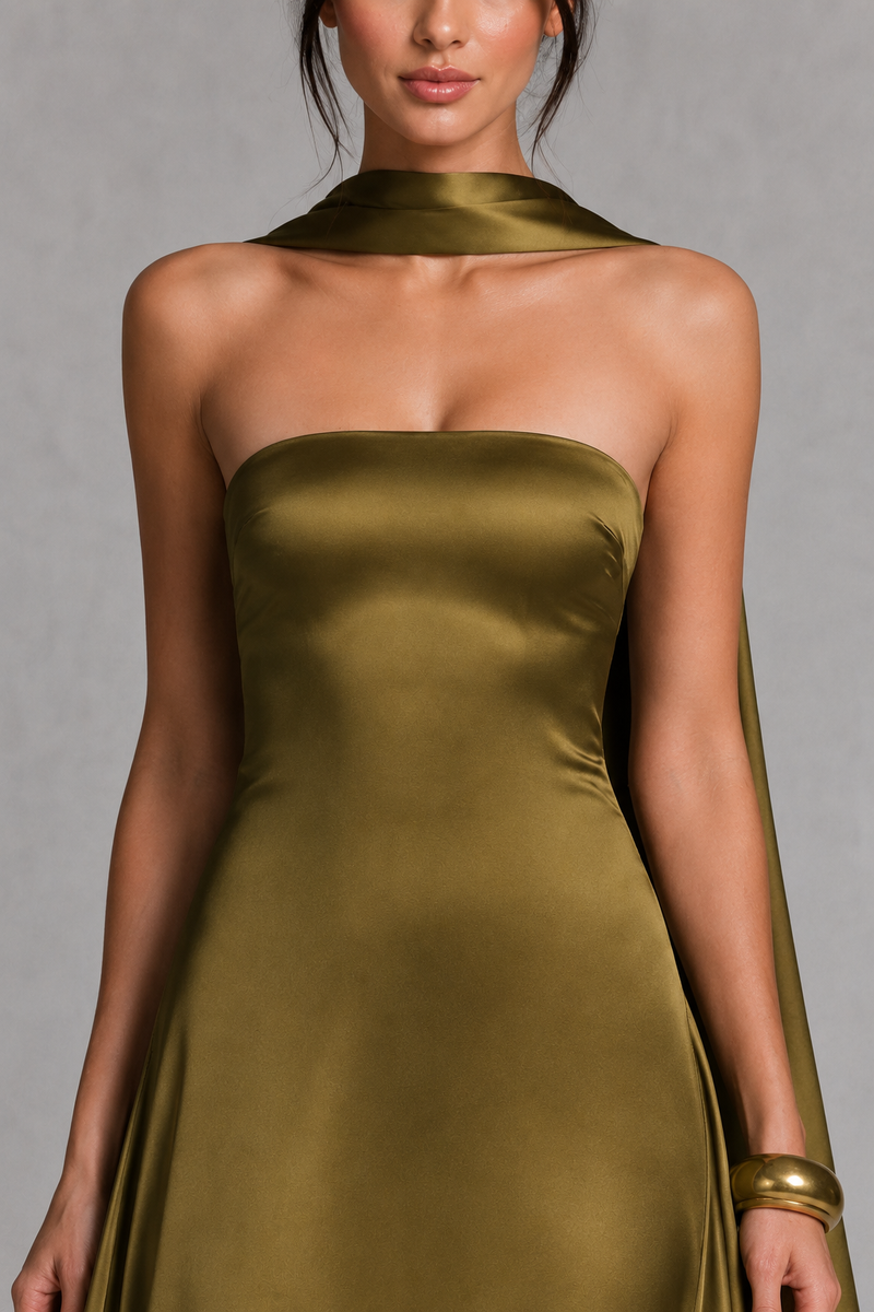 Woman wearing a strapless gold dress against a gray background