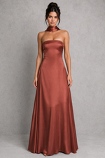 Woman wearing a strapless rust-colored evening gown against a gray background