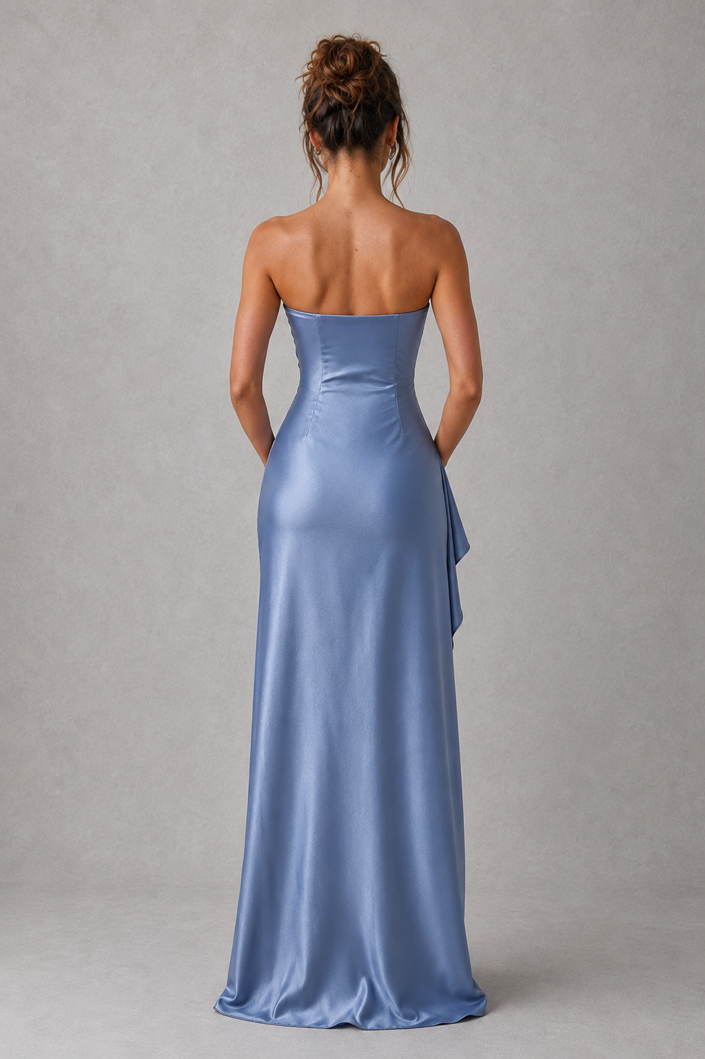 Woman wearing a strapless blue evening gown against a gray background