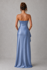 Woman wearing a strapless blue evening gown against a gray background
