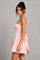 Woman wearing a pink strapless dress against a gray background