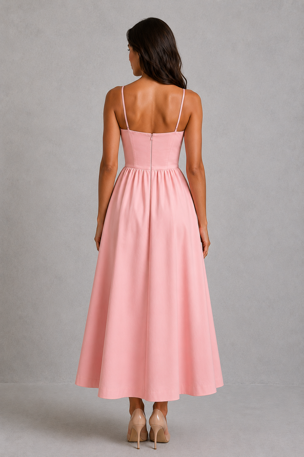 Woman wearing a pink dress with thin straps against a gray background
