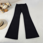 Black bell-bottom pants on a light surface with decorative elements.