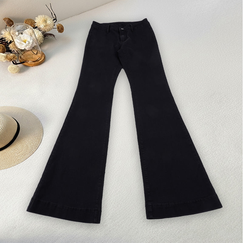 Black bell-bottom pants on a light surface with decorative elements.