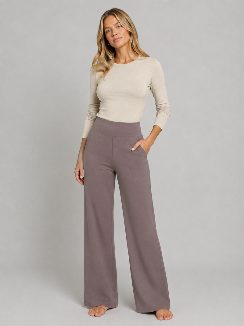 Woman wearing a beige top and brown pants on a gray background