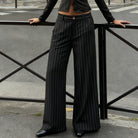 Person wearing black pinstripe pants standing on a street.