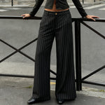 Person wearing black pinstripe pants standing on a street.