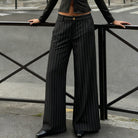 Person wearing black pinstripe pants standing on a street.