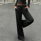 Person wearing black pinstripe pants and a matching top on a street.