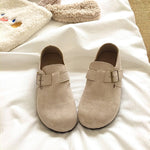 Pair of beige clogs with buckles on a white surface