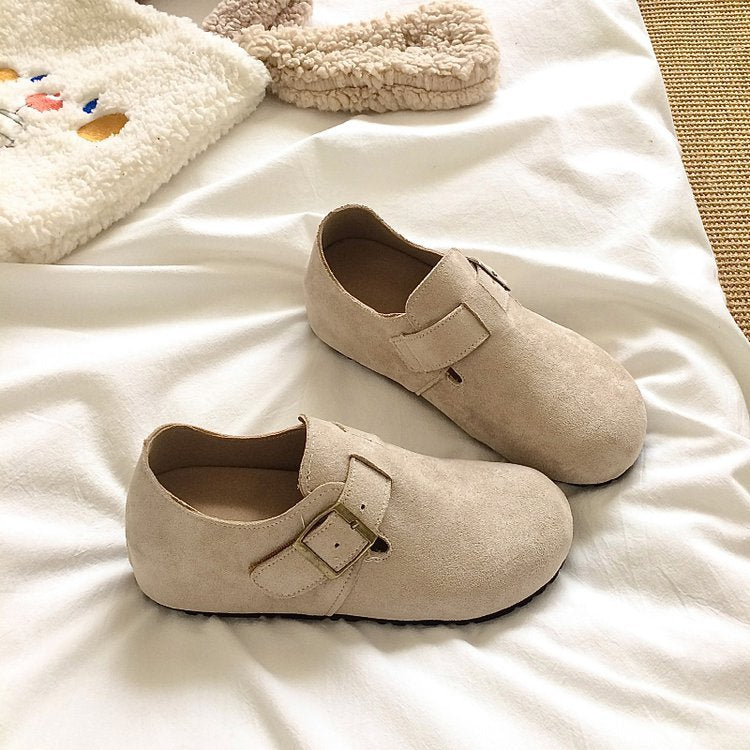 Pair of beige shoes with buckles on a white surface