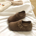 Pair of brown suede shoes with a buckle on a white surface