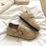 Pair of beige slippers with buckles on a white surface