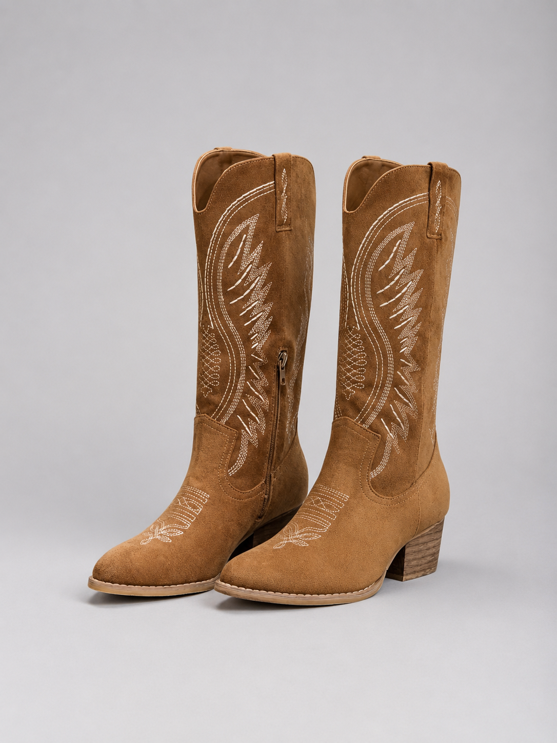 Pair of brown cowboy boots with white embroidery on a gray background