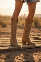 Tan cowboy boots with detailed design on a neutral background